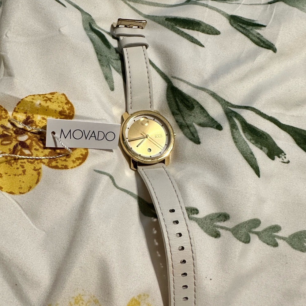 Movado Bold Watch with white strap gold dial.